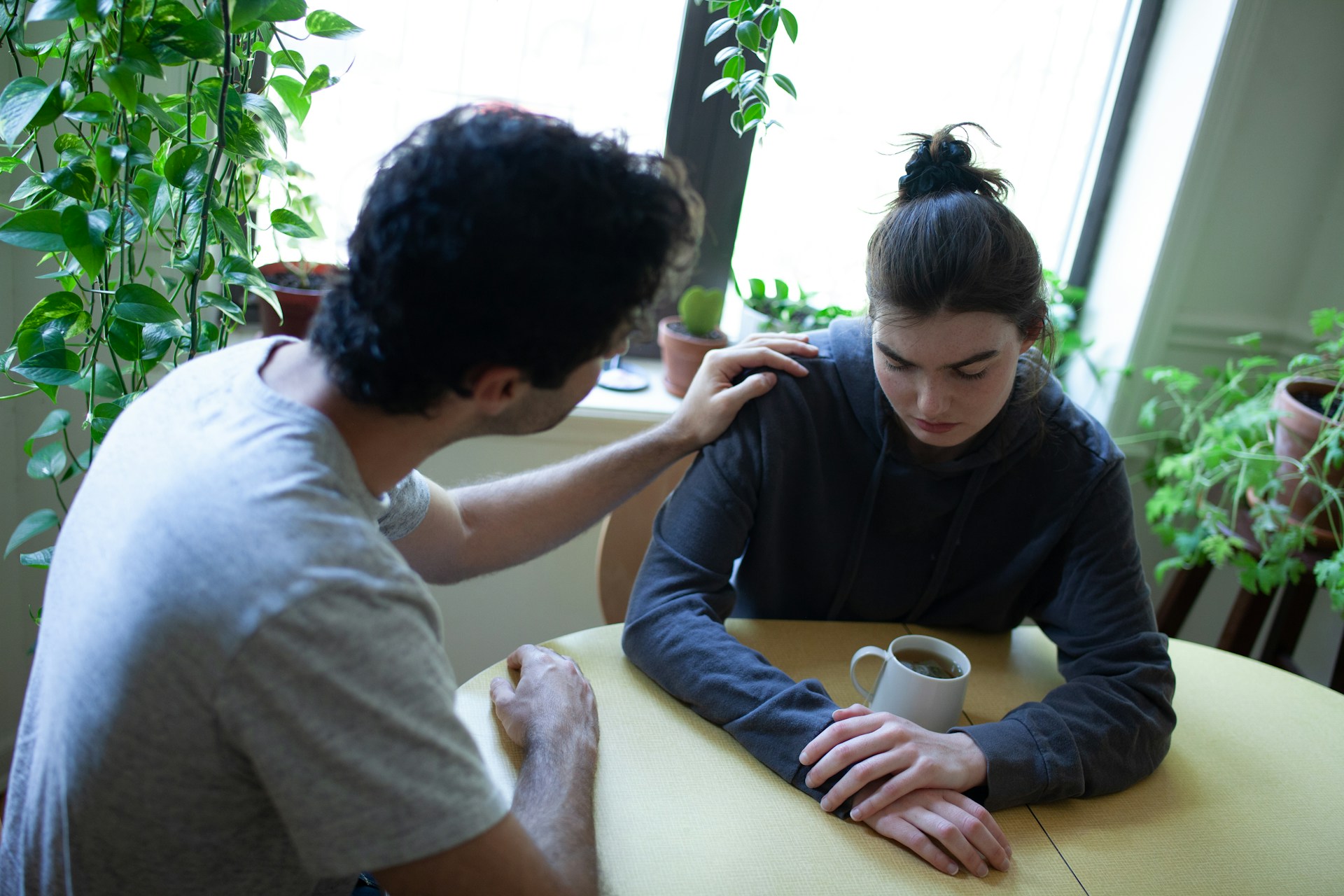 Man gently resting his hand on his partner’s shoulder during a quiet conversation, representing subtle ways avoidant partners may show love and care.